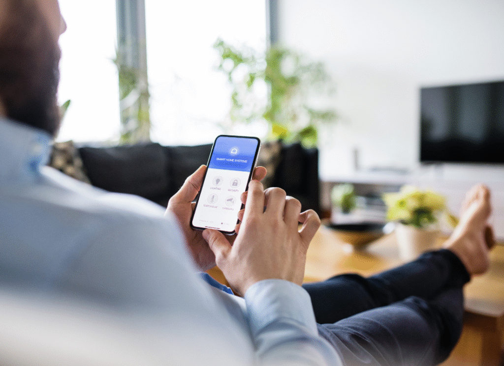 Styr ditt hem med smart teknik – Åsa Elkoncept Person sitter bekvämt i soffan och styr sitt smarta hem via mobiltelefonens app.