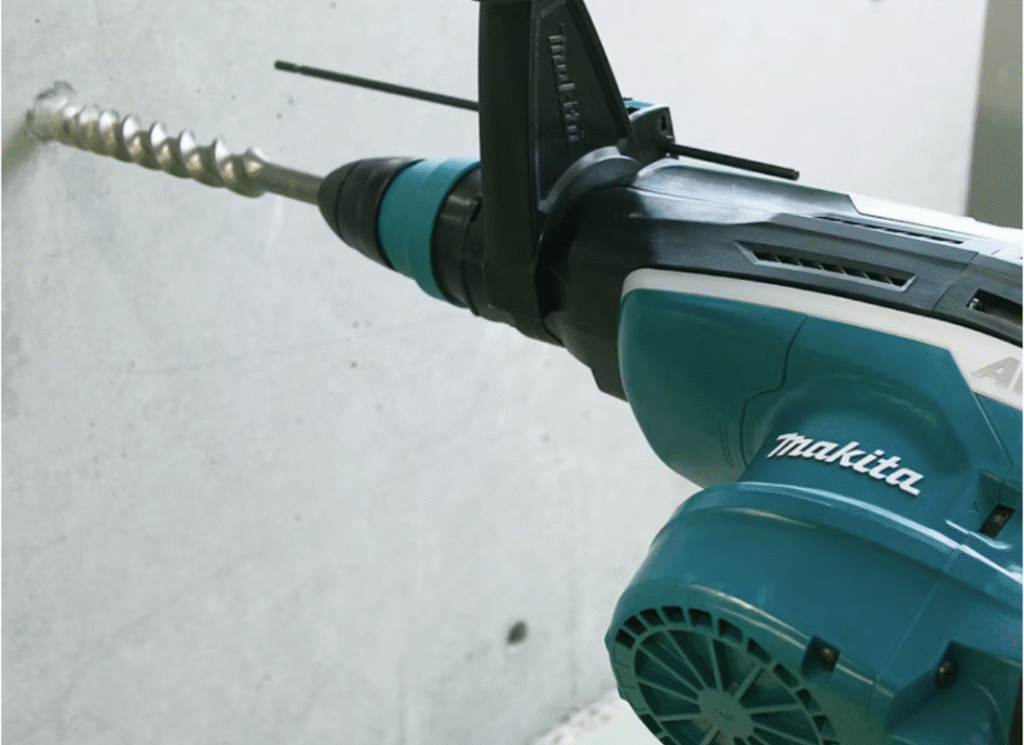 Makita HR5212C i arbete – kraftfull borrning i betong Makita HR5212C kombihammare borrar i betongvägg, visar maskinens kraft och precision i arbete.